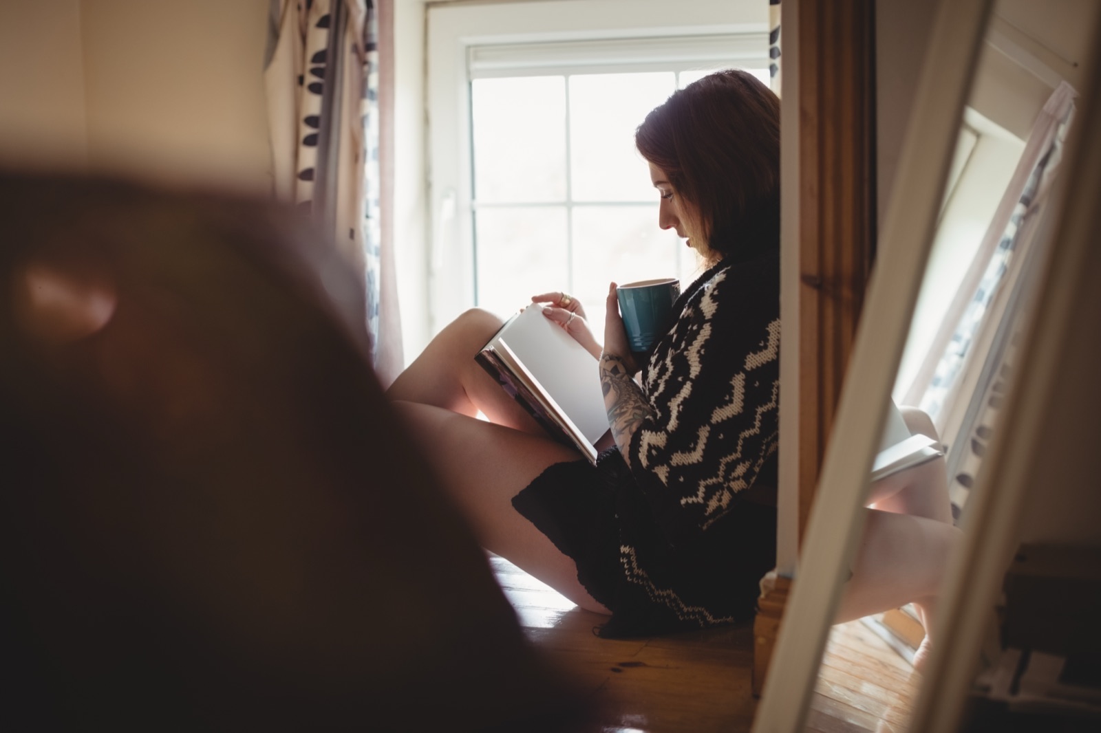 Femme qui lit un livre près d'une fenêtre